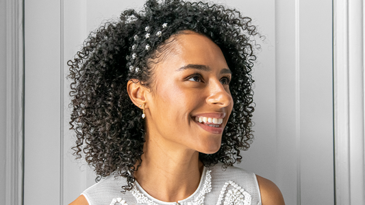 Vrouw met zwart, krullend haar, gestyled voor een bruiloft