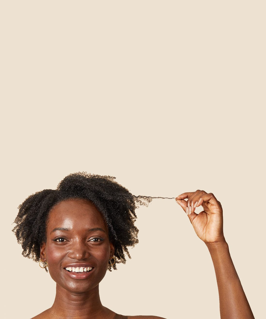 glimlachende, zwarte vrouw die een paar lokken van haar zwarte, warrige haar uitsteekt