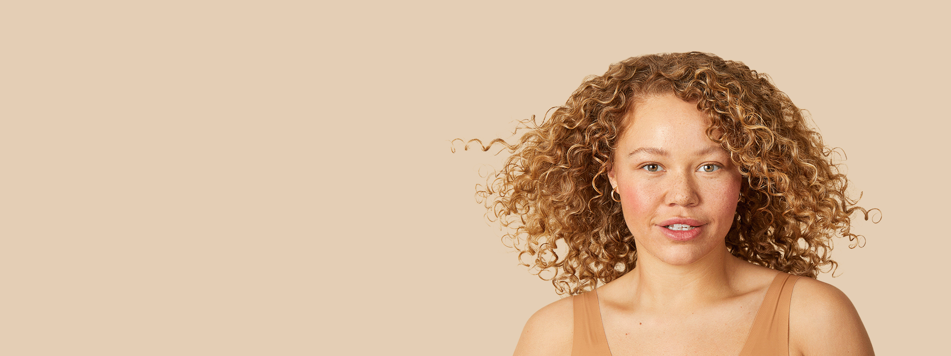 close up of a woman with strawberry-blonde curly hair facing the camera