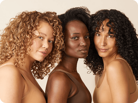 drie vrouwen met krullend haar kijken naar de camera