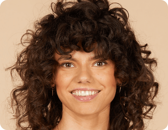 close-up van een glimlachende vrouw met golvend bruin haar